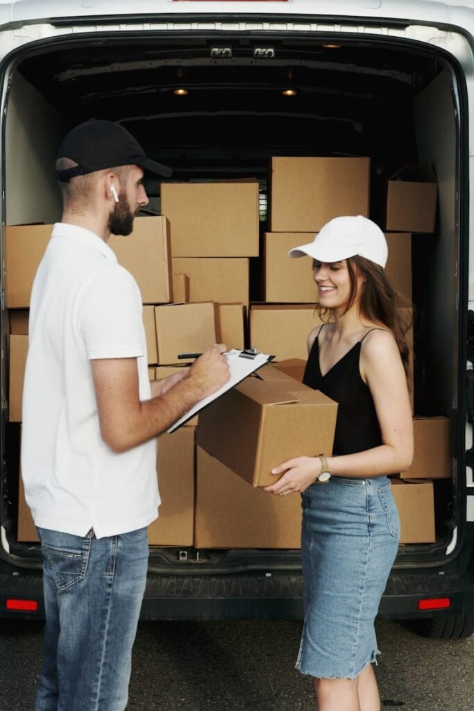 pexels-photo-5025502-5025502 A delivery person hands a package to a woman from a van full of parcels outdoors.